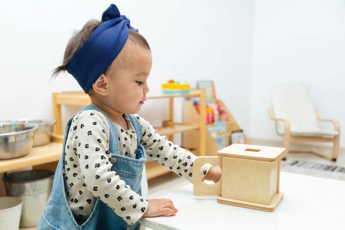 Small toddler playing with a wooden learning shape box